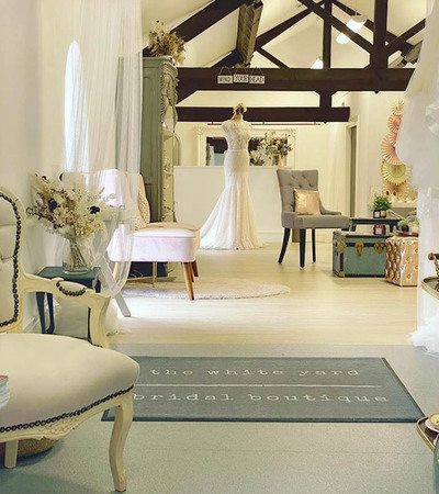 Interior of a bridal boutique with wedding dresses and white chairs