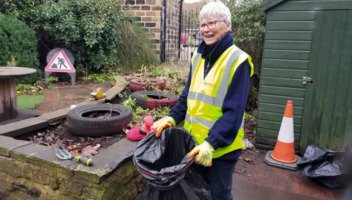 A volunteer collecting green waste from a small garden at Elsecar Heritage Centre.