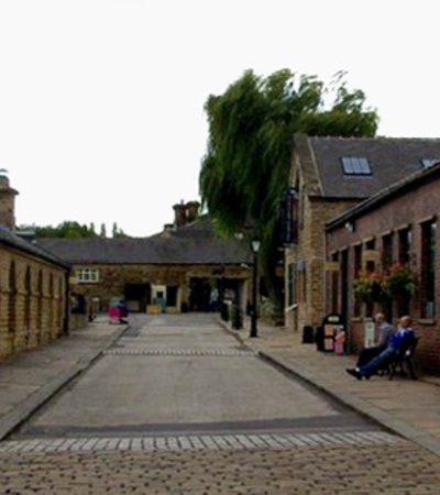 A cobbled street with buildings on either side at Elsecar Heritage Centre