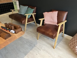 Two comfortable brown chairs with a wooden table infront of them in the visitor centre