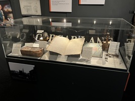 Glass display case with historic objects inside, including a miners lamp, book and brick