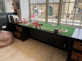A children's train set on a table in front of the window.