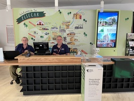 Visitor centre Reception desk, with 2 members of staff sat behind it. Wheelchair accessible low counter to the left.