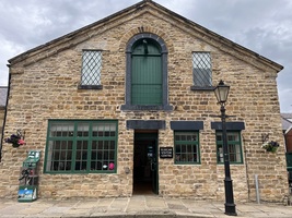 Visitor Centre entrance. An open green door. Windows with green frames and an old Victorian street lamp.