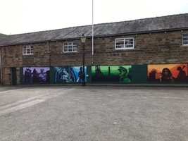 Different coloured murals depicting miners on the outside wall of a row of buildings.