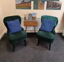 Two green comfortable chairs with a table in between them