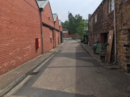 A pathway leading to the right of the heritage centre towards the train tracks with independent shops along the right hand side
